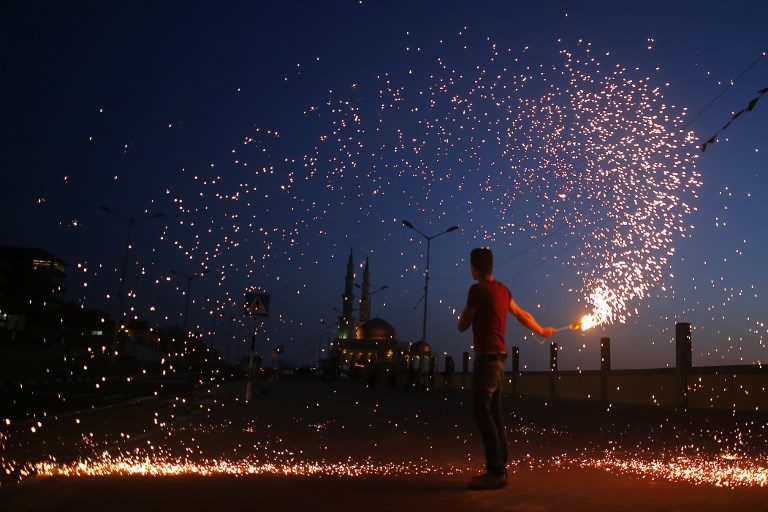 WAITING FOR THE MOON. A Palestinian youth waves a sparkler next a mosque in Gaza City on May 16, 2018, as the faithful prepare to start the Muslim holy fasting month of Ramadan. Photo by Mohammed Abed/AFP  