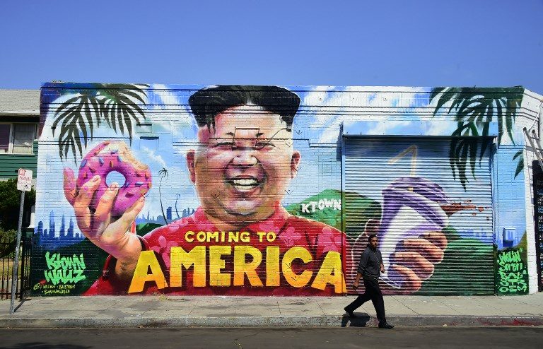KOREATOWN. A pedestrian walks past a mural titled 'Coming To America' depicting North Korean leader Kim Jong-un holding a doughnut and milkshake, made by graffiti artists @welinoo, @balstroem and @sorenarildsen in Los Angeles, California, on May 14, 2018. Photo by Frederic Brown/AFP   