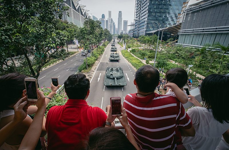 People watch a column of military and civil defense vehicles making their way to their starting positions prior to the National Day Parade in Singapore, 09 August 2015. Photo by Tom White/EPA 