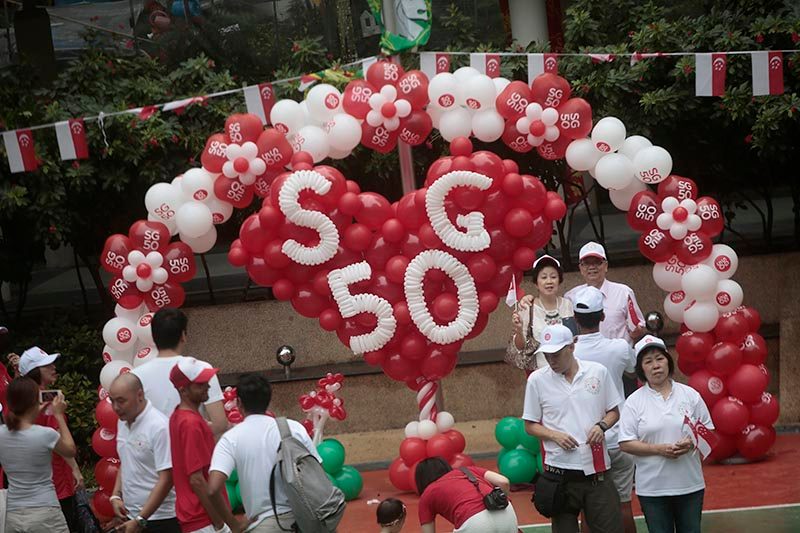 Singaporeans pose for photographs with a balloon sculpture spelling out 'SG50' during a National Day Observance Ceremony. Photo by Wallace Woon/EPA 