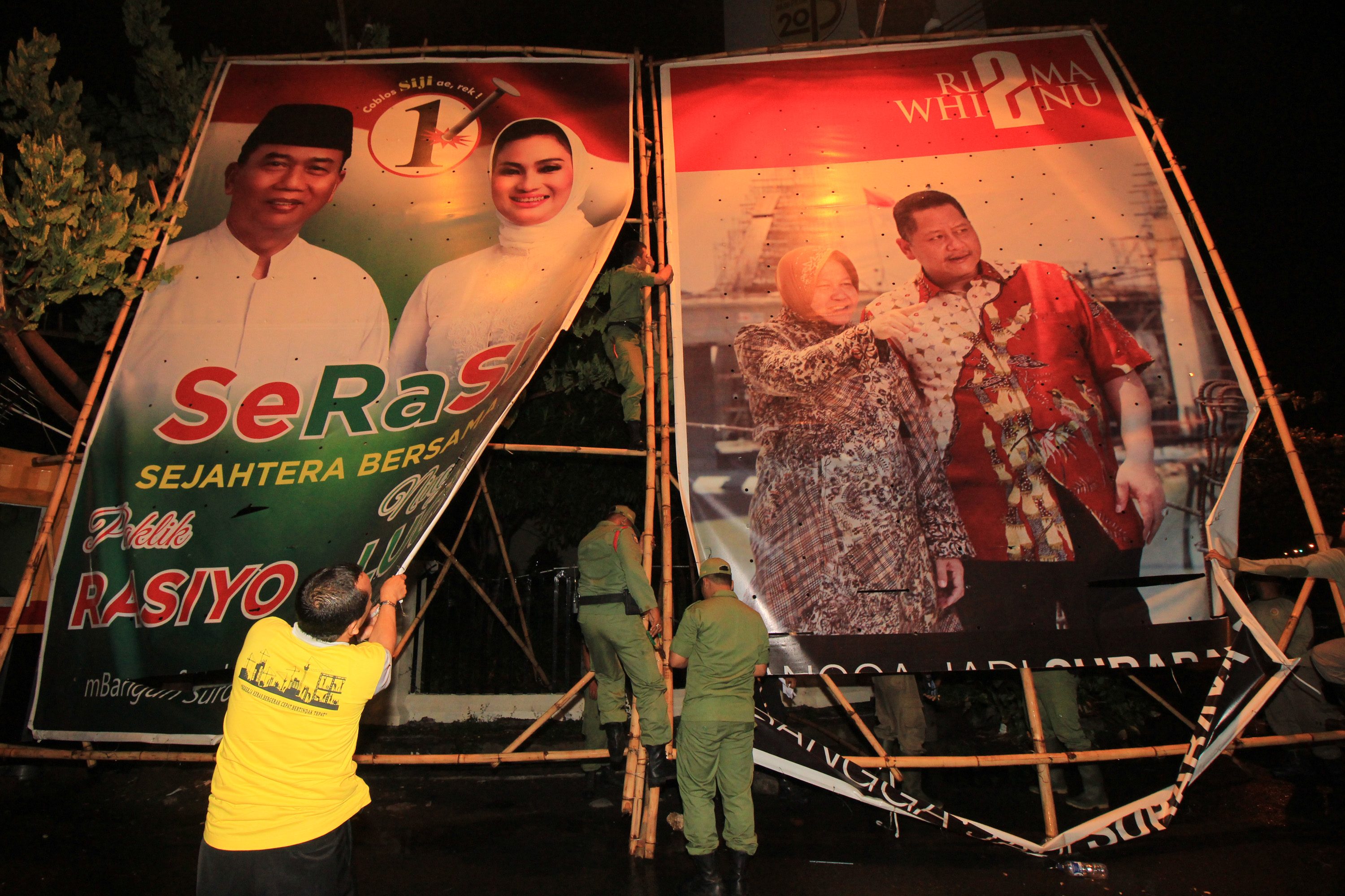 Petugas membongkar alat peraga kampanye bergambar pasangan calon wali kota/wakil wali kota dalam Pilkada Surabaya 2015 di Surabaya, Jawa Timur, pada 6 Desember 2015, yang sudah melampaui masa kampanye. Foto oleh Didik Suhartono/Antara  