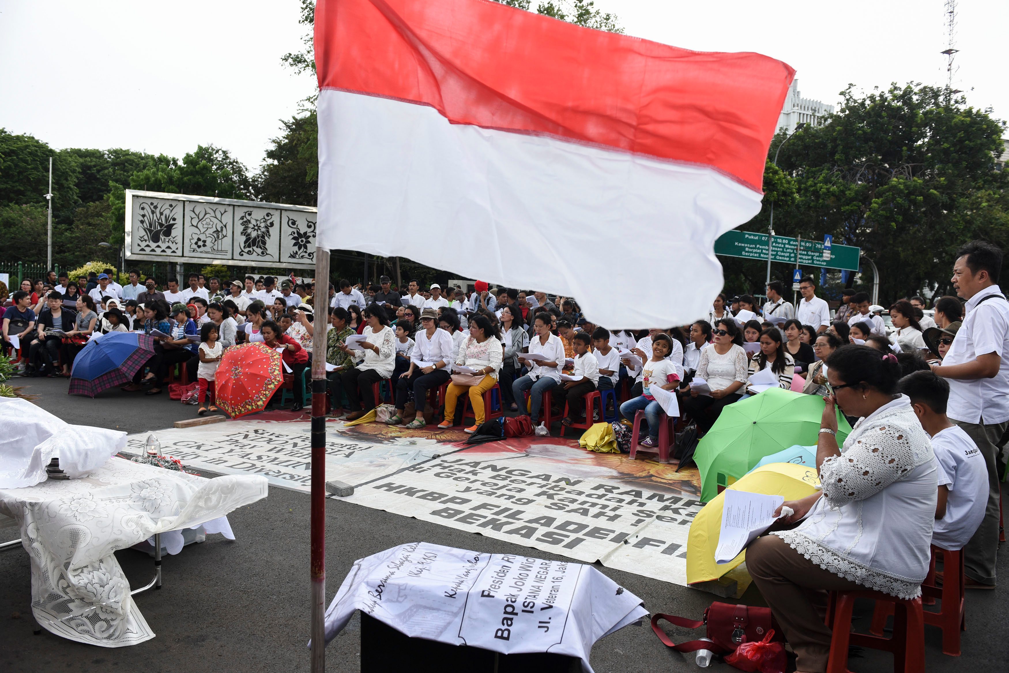 Sebuah bendera Merah Putih terbentang di hadapan Jemaat GKI Yasmin Bekasi dan HKBP Filadelfia Bogor yang mengikuti ibadah perayaan Natal di seberang Istana Merdeka, Jakarta, pada 25 Desember 2016. Foto oleh Hafidz Mubarak/Antara
 