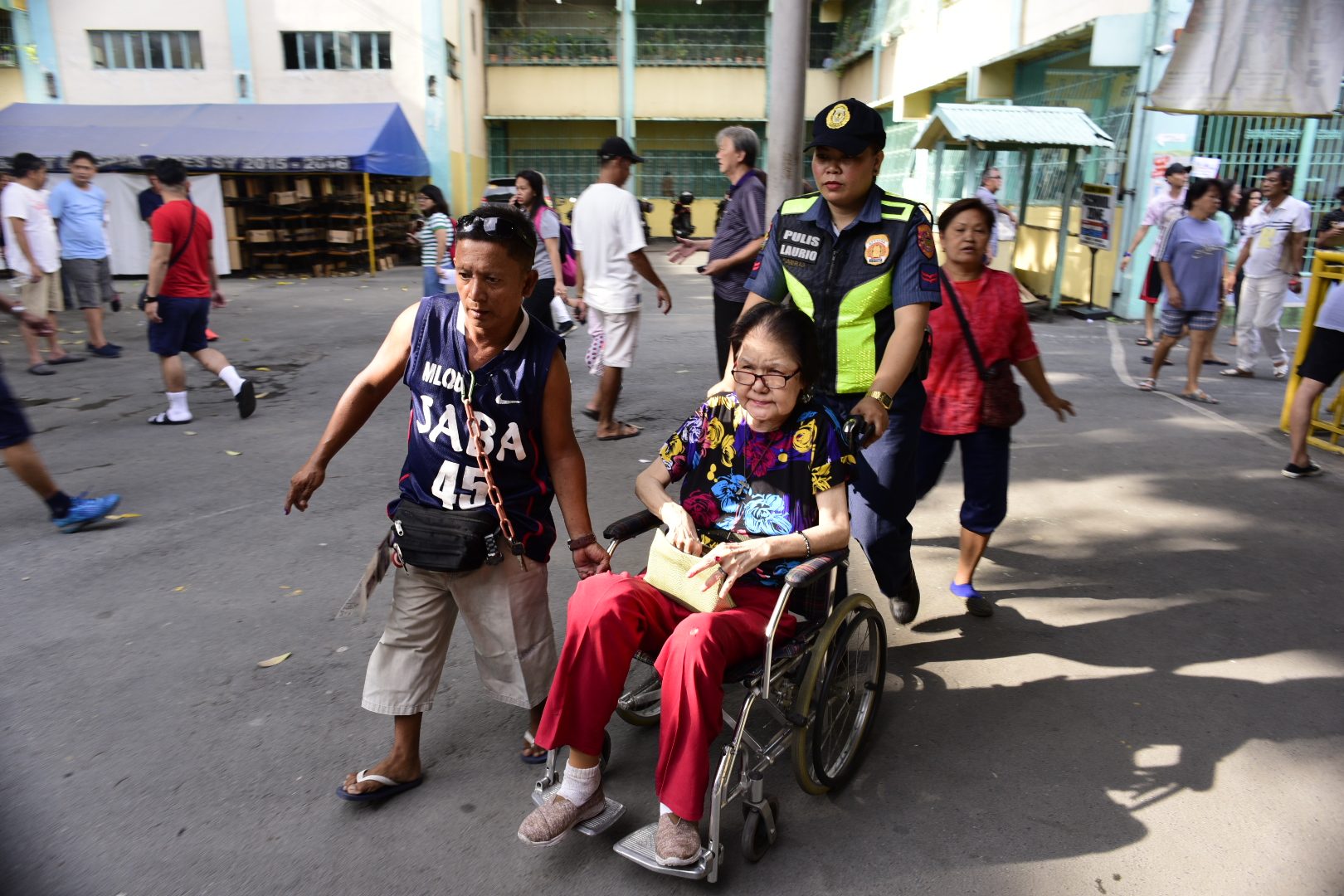 PASAY. A police officer assists a PWD at P Burgos Elementary School. Photo by Rob Reyes/Rappler  