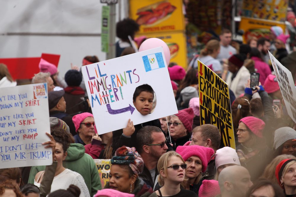 A boy holds a sign saying 'Lil' immigrants matter.' 