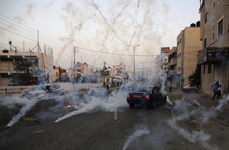 GASSED. Palestinian men run for cover from tear gas during clashes between demonstrators and Israeli security forces at the Qalandiya checkpoint in the occupied West Bank, on July 23, 2017. Photo by Abbas Momani/AFP   