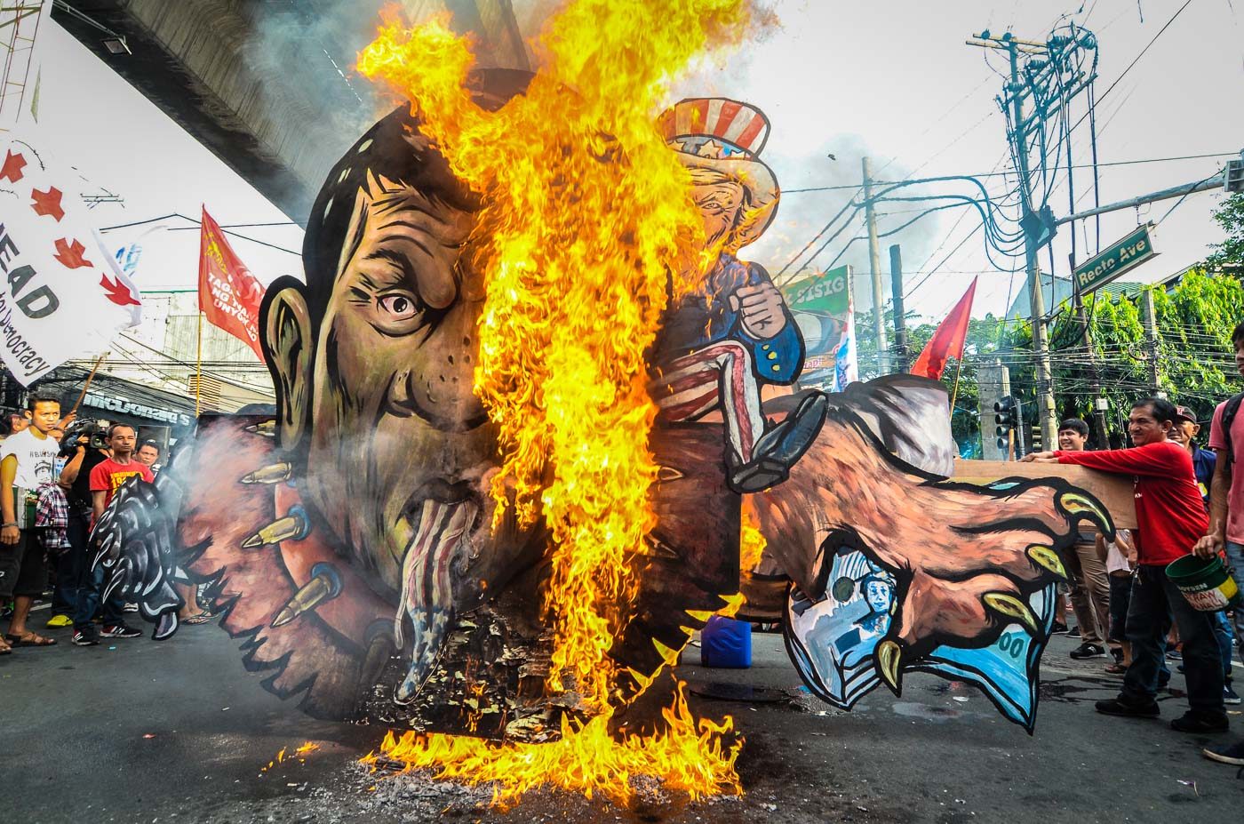 PATUNG.  Pengunjuk rasa anti-Duterte membakar patung Presiden Rodrigo Duterte yang digambarkan sebagai anjing peliharaan Presiden AS Donald Trump yang berwajah ular.  Foto oleh Maria Tan/Rappler  