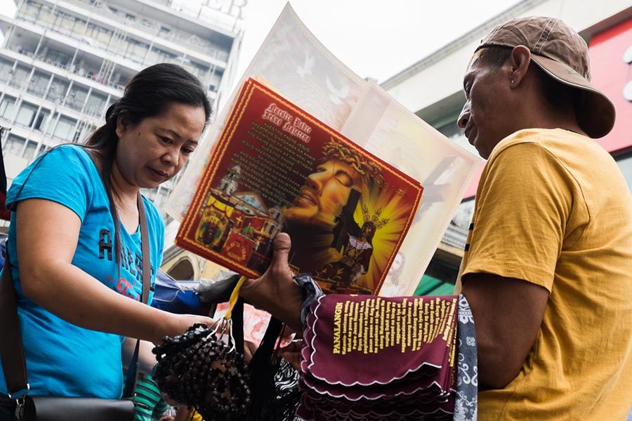 PATRON. A woman buys a Nazareno towel from one of the vendors in Quiapo. The towels have prayers on them and sell for P15-P20 apiece. 
