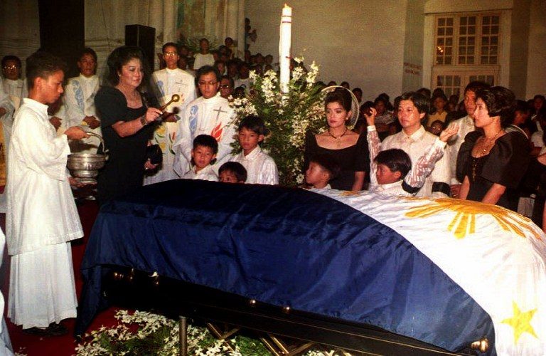 MASS. Former First Lady Imelda Marcos sprinkles holy water on the flag-draped coffin of her late husband Ferdinand Marcos during a memorial Mass at the Saint William Cathedral in the Philippines while her family watches. Photo from AFP 