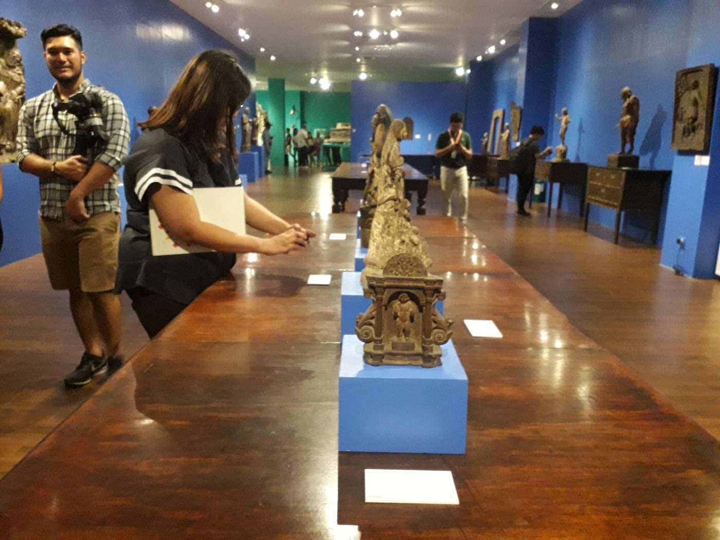SNEAK PEEK. Members of the media take photos of wooden carvings made by Filipino artists for churches. Photo by Pia Ranada/Rappler 