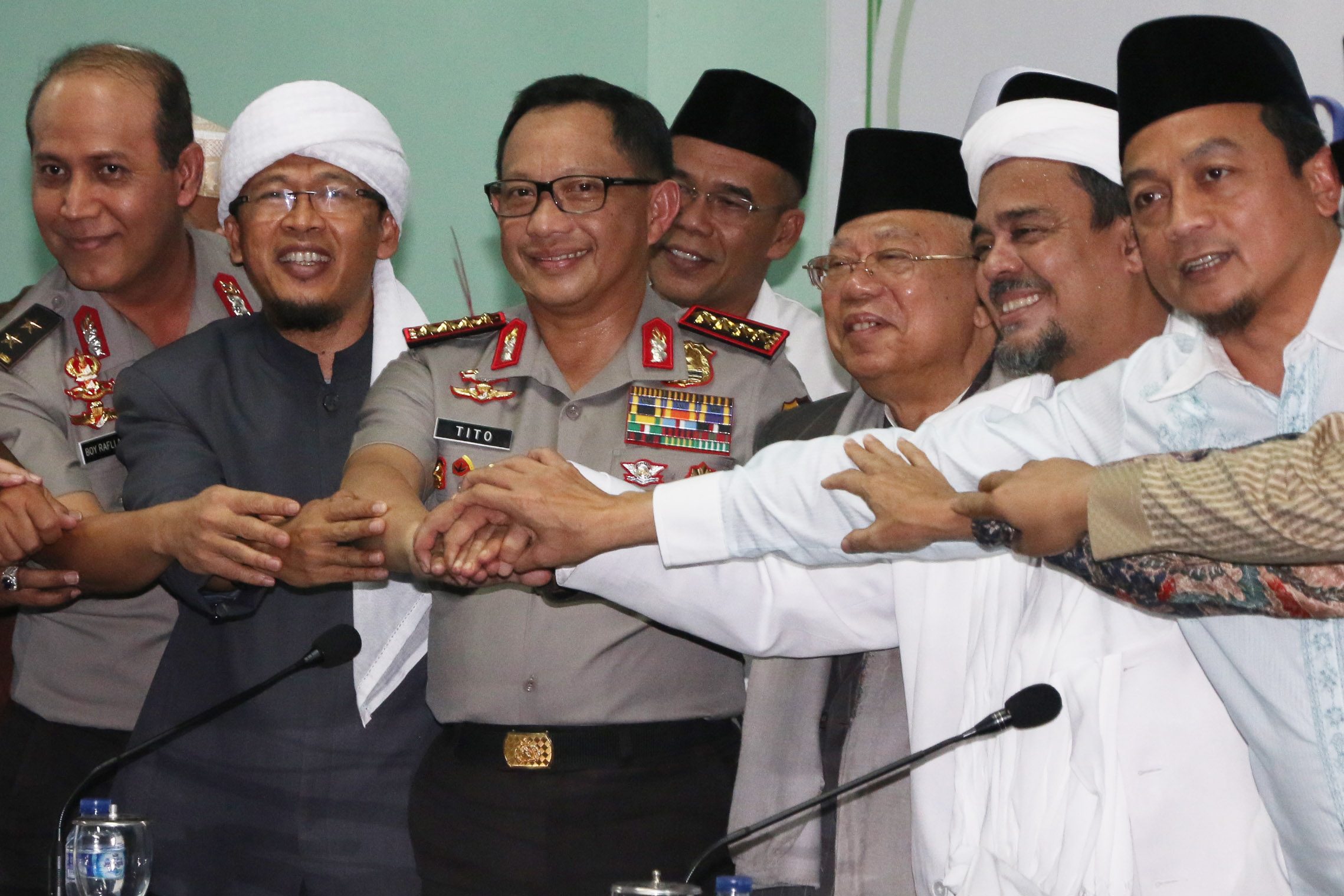 JABAT TANGAN. Kapolri Jenderal Pol Tito Karnavian (ketiga kiri) bersama Ketua Majelis Ulama Indonesia (MUI) Ma'ruf Amin (ketiga kanan), Kadivhumas Polri Irjen Pol Boy Rafli Amar (kiri), Ketua FPI Habib Rizieq Syihab (kedua kanan), Ketua Gerakan Nasional Pengawal Fatwa (GNPF) MUI Bachtiar Nasir (kanan), dan Ulama Abdullah Gymnastiar (kedua kiri) berjabat tangan usai memberikan konferensi pers jelang aksi bela Islam jilid III di Gedung MUI, Jakarta, Senin, 28 November. Foto oleh Rivan Awal Lingga/ANTARA 