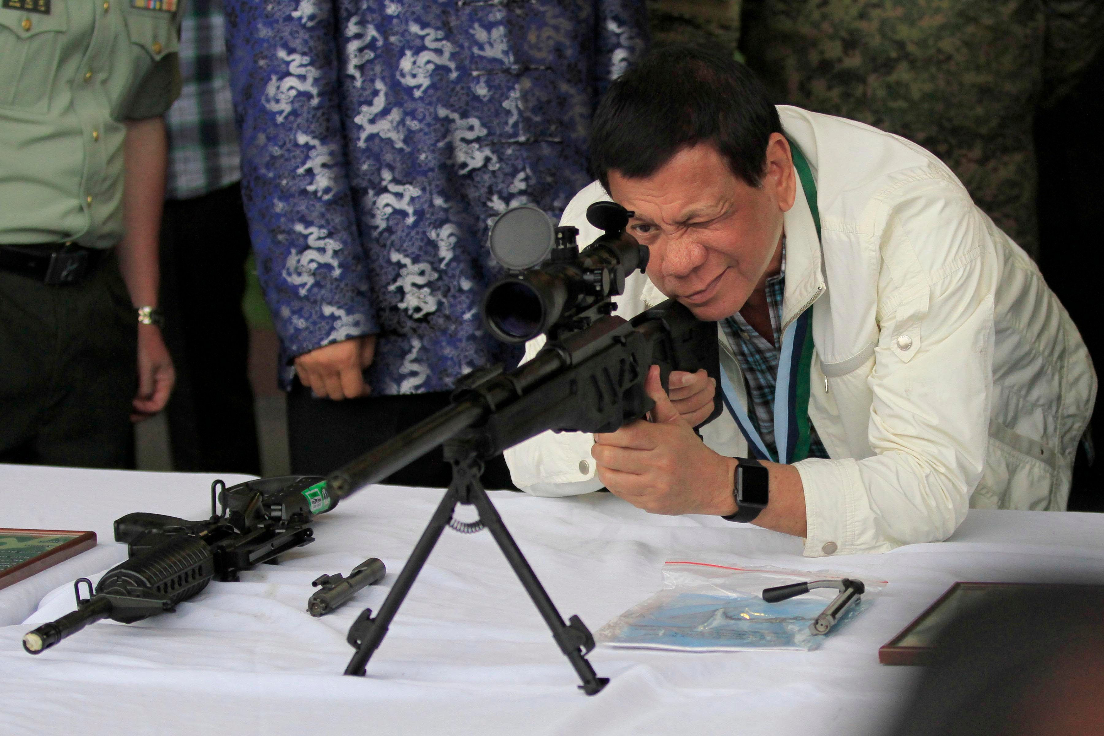 HITTING THE MARK. President Rodrigo Duterte looks through the scope of a sniper rifle donated by China after an event in Clark Air Base in Pampanga on June 28, 2017. Malacanang Photo   