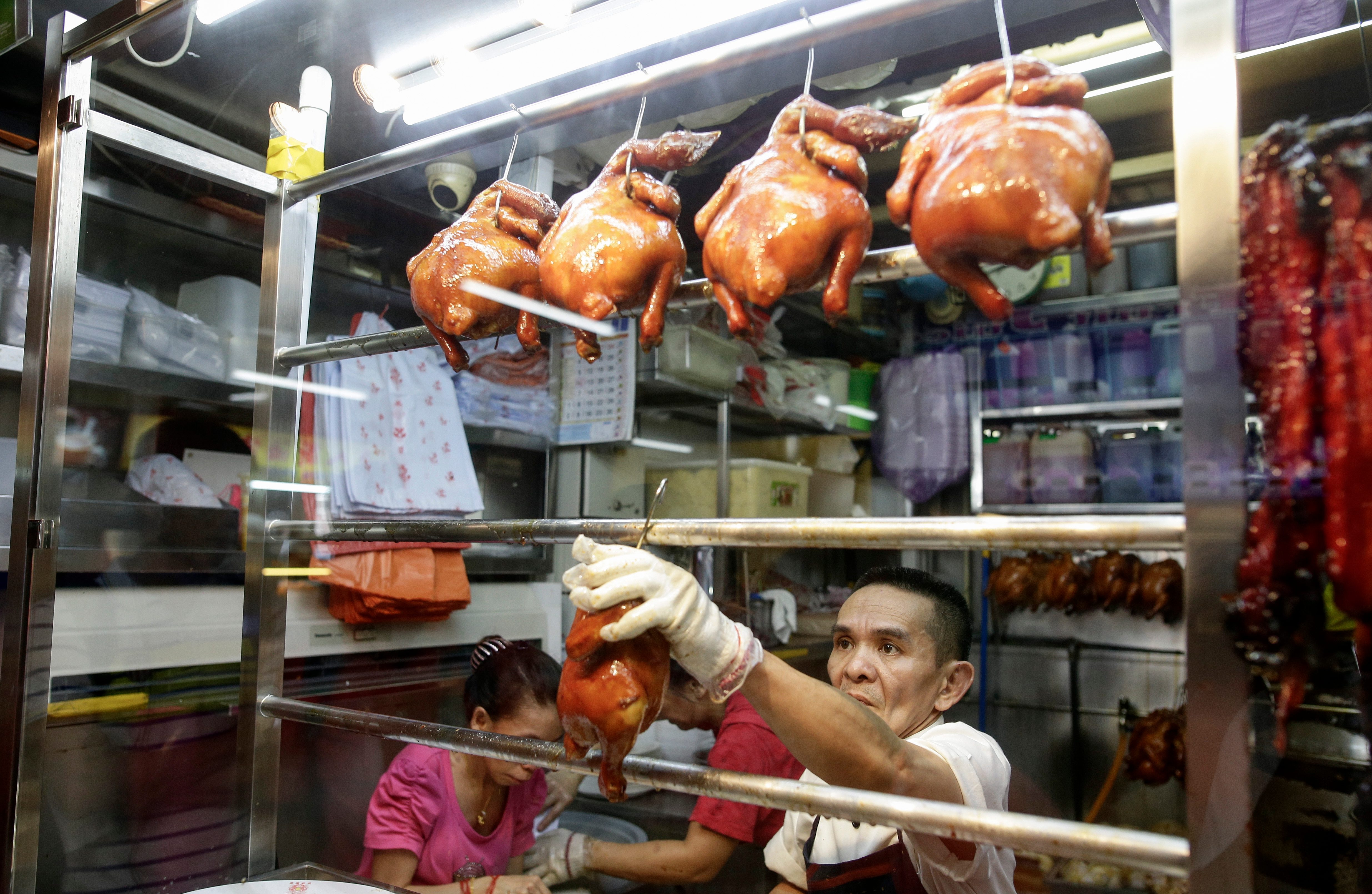 CHAN HONG MENG. Chan Hong Meng, owner of Hong Kong Soya Sauce Chicken Rice and Noodle, hangs a soy sauce chicken on display at his store in Singapore. Photo by Wallace Woon/EPA 