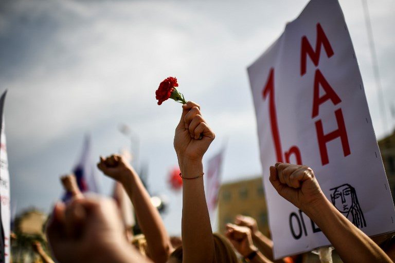 A member of the Greek Communist Labour Union (PAME) holds a carnation during the May Day celebrations in Athens on May 01, 2018. Photo by Aris Messinis/AFP 