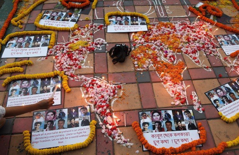 IN MEMORY OF. An Indian photojournalist lights a candle during a vigil for 10 Afghan journalists who were killed in a targeted suicide bombing and on the eve of World Press Freedom Day in Kolkata on May 2, 2018. Photo by Dibyangshu Sarkar/AFP  