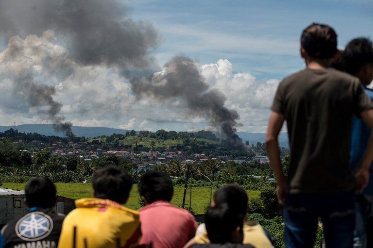 UP IN SMOKE. Marawi residents watch as smoke billows from houses after aerial bombings by air force planes on Maute rebels' positions in Marawi on June 17, 2017. Photo by Noel Celis/AFP   