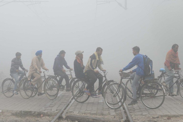 POOR VISIBILITY. Indian commuters ride over tracks at a railway crossing amid heavy smog in Amritsar on November 9, 2017. Photo by Narinder Nanu/AFP 