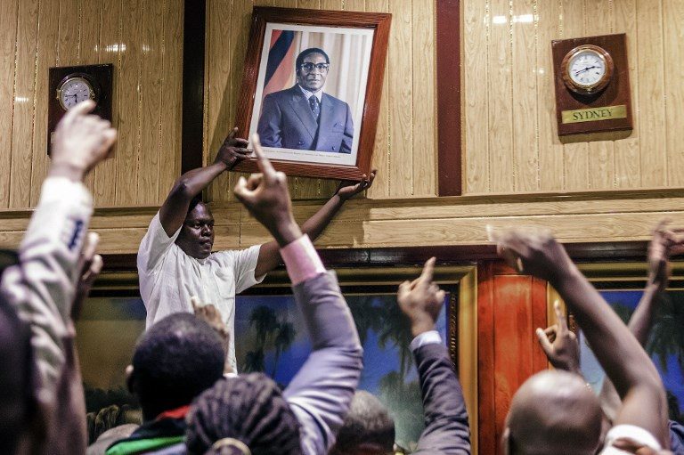 OUT. People remove, from the wall at the International Conference center, where parliament had their sitting, the portrait of former Zimbabwean President Robert Mugabe after his resignation on November 21, 2017 in Harare. Photo by Jekesai Njikizana/AFP   