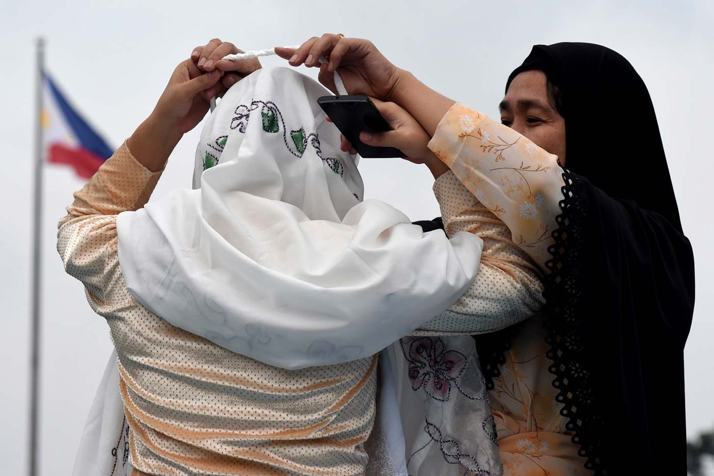 FIXING VEILS. A woman helps another fix her veil during the celebration of Eid'l Adha at the Quezon Memorial Circle on August 21, 2018. Photo by Angie de Silva/Rappler  