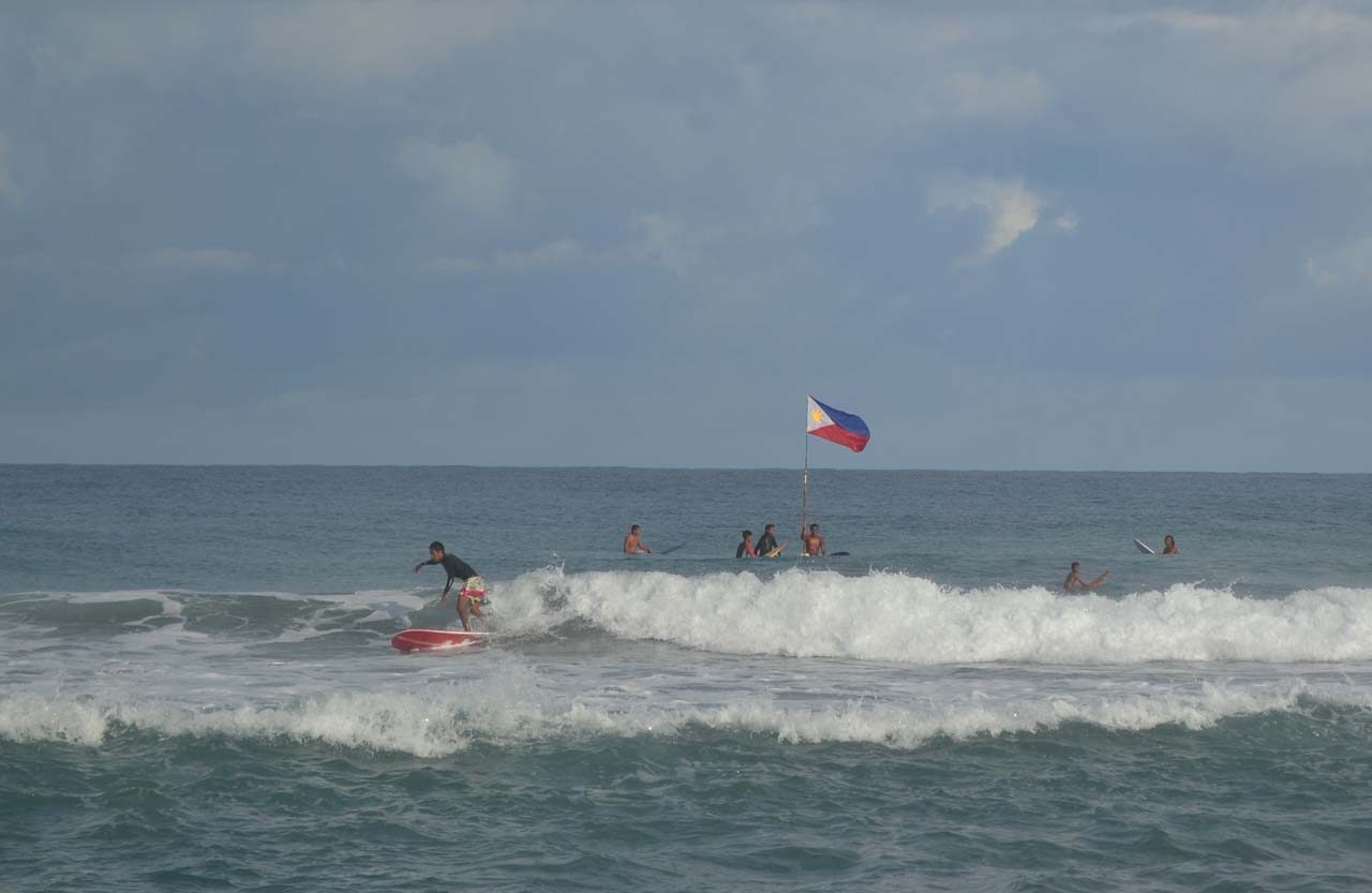 OUT TO SEA. Surfers paddle out to bring the Philippine flag to the West Philippine Sea. Photo by Charlon Kim 