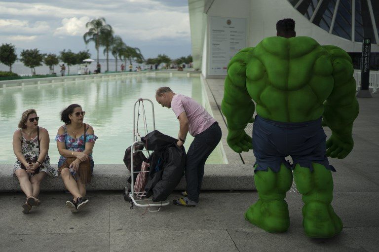 BREAK. Street artist Henrique Soares (R) in a costume of the comic character, Hulk, takes a break after performing in Rio de Janeiro, Brazil, on November 18, 2017. Photo by Leo Correa/AFP  