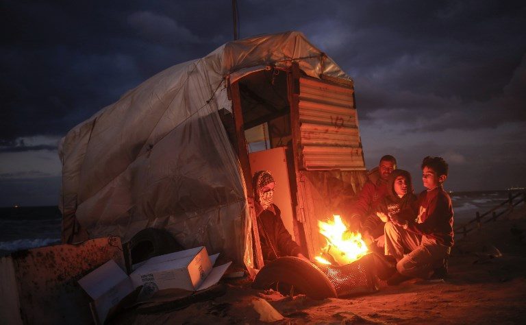 CONFLICT ZONE. Palestinian children warm up around a fire by a shack along the beach in Gaza City on November 22, 2017. Photo by Mohammed Abed/AFP   