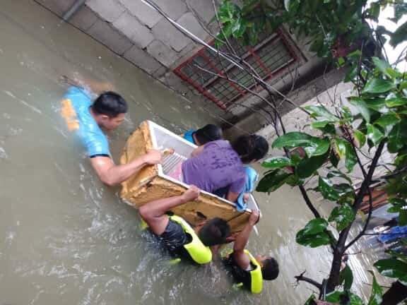 IMPROVISED BOAT. Police use a junk fridge to move a woman and her infant in Laoag City, Ilocos Norte, on August 24, 2019. Photo by Edison Deus  