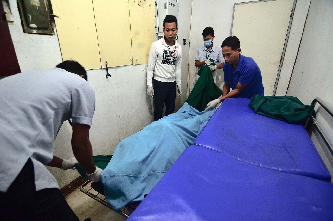 MORGUE. Hospital workers handle the corpse of Fr Marcelito Paez in the Gonzales General Hospital morgue in San Leonardo, Nueva Ecija, on December 5, 2017. Photo by Maria Tan/Rappler 