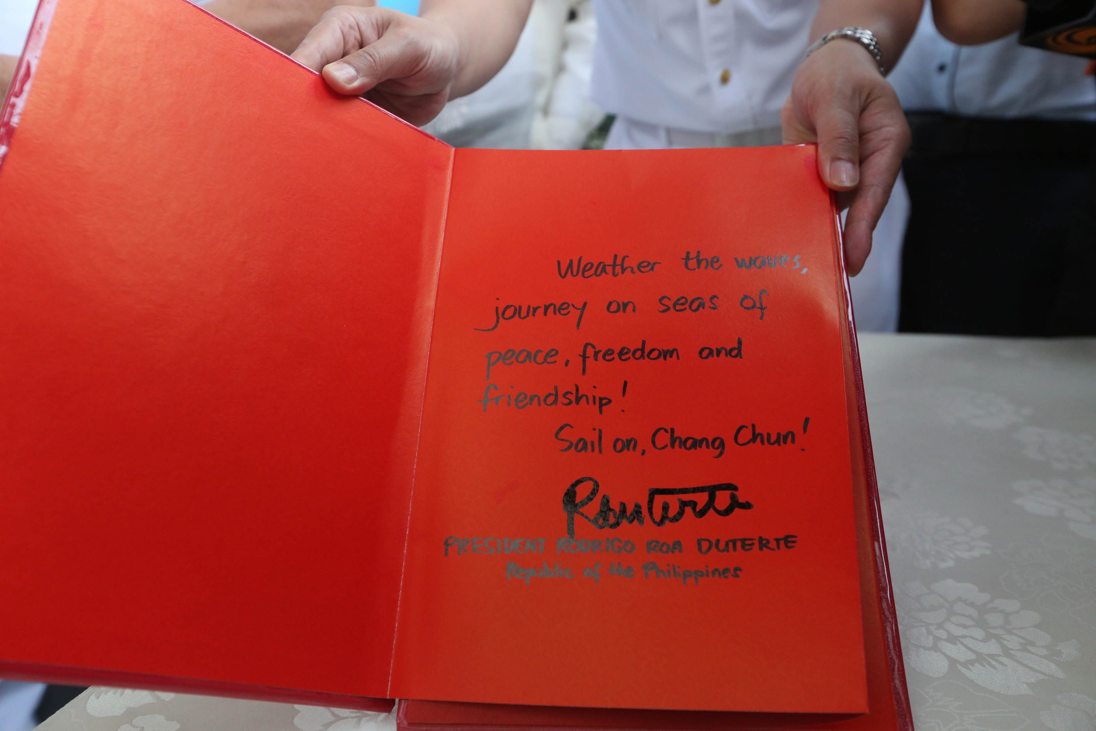 'SEAS OF PEACE.' The Philippine President writes a message of peace as he signs Chang Chun's guest book. 