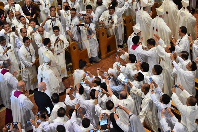 Priests take a photograph of Pope Francis as he arrives to lead a mass for local Catholic leaders at the Manila Cathedral on January 16, 2015. Photo by Giuseppe Cacace/AFP