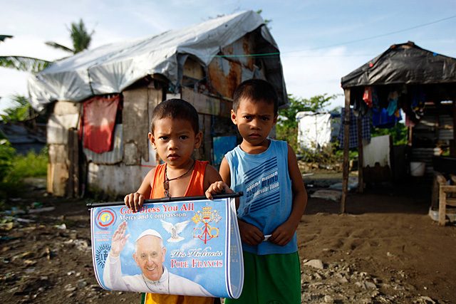 Filipino children hold a portrait of Pope Francis in village which was severely damaged by the 2013 Typhoon Yolanda/Haiyan in Tacloban City on January 16, 2015. Pope Francis is scheduled to visit Tacloban and Palo on January 17, 2015. Photo by Jay Labra/EPA