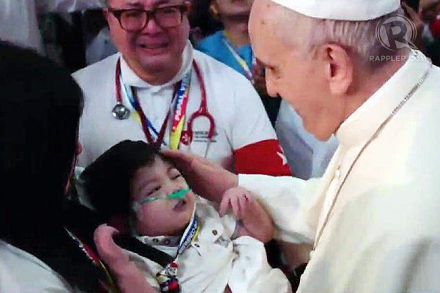 Pope Francis touches a sick child as he enters the Mall of Asia Arena for the meeting with families, January 16, 2015. Rappler photo