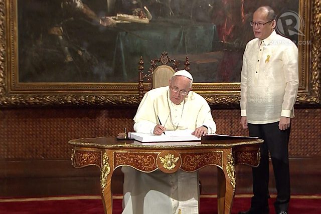 Pope Francis signs the official Guest Book at the Malacañang Palace, as Philippine President Benigno Aquino III looks on, January 16, 2015. Rappler photo