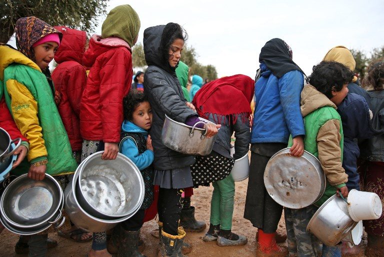 FOOD LINE. Syrian children queue to receive food distributed by humanitarian aid workers at a makeshift camp for displaced people in the village of Yazi Bagh along the border crossing between Syria and Turkey in north Aleppo on February 7, 2018. Photo by Nazeer Al-Khatib/AFP   