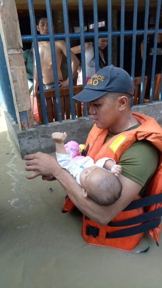 SAFETY. FIRST A rescue worker carries a baby to dry ground. Photo from Davao CIO   