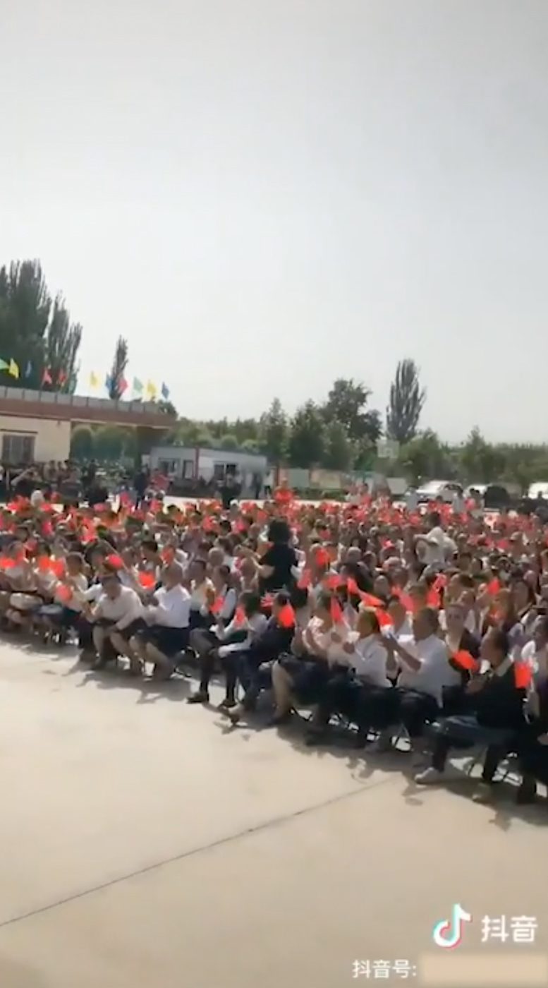 CONCERT. Crowds wave Chinese flags at what appears to be a propaganda concert in Yopurga County, near Kashgar, Xinjiang 