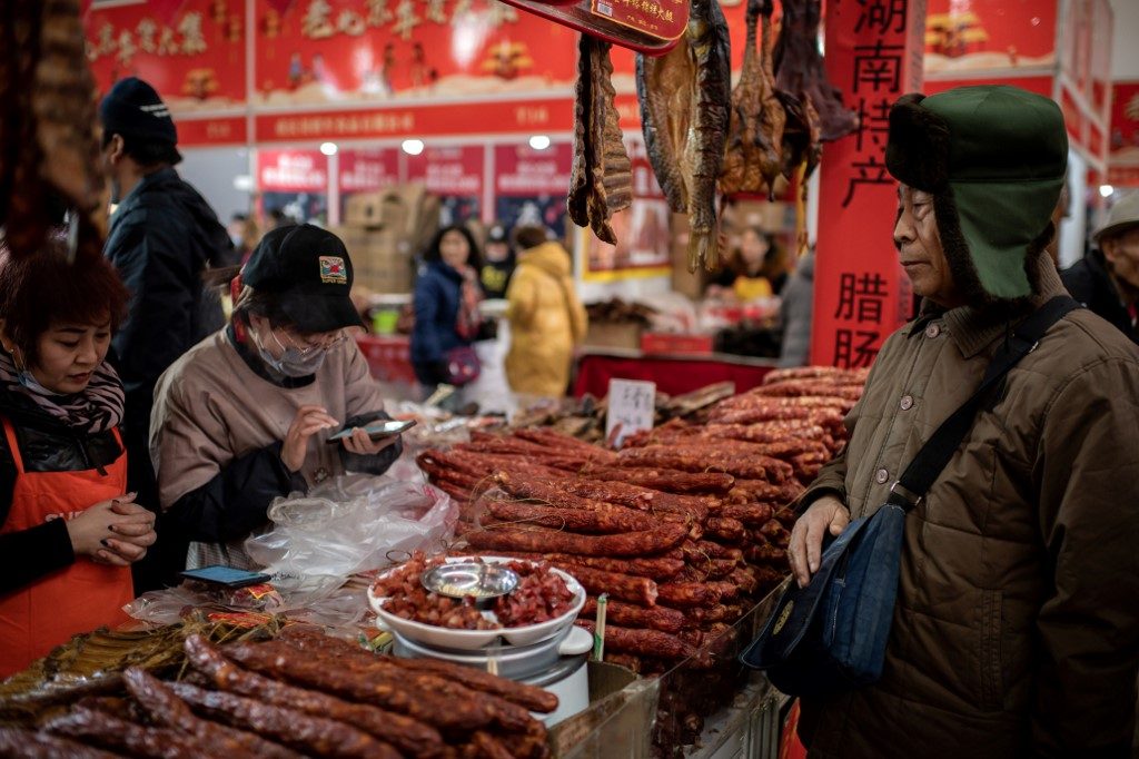 SLOWING ECONOMY. A customer buys dried sausages at a market in Beijing on January 15, 2020. Photo by Nicolas Asfouri/AFP 