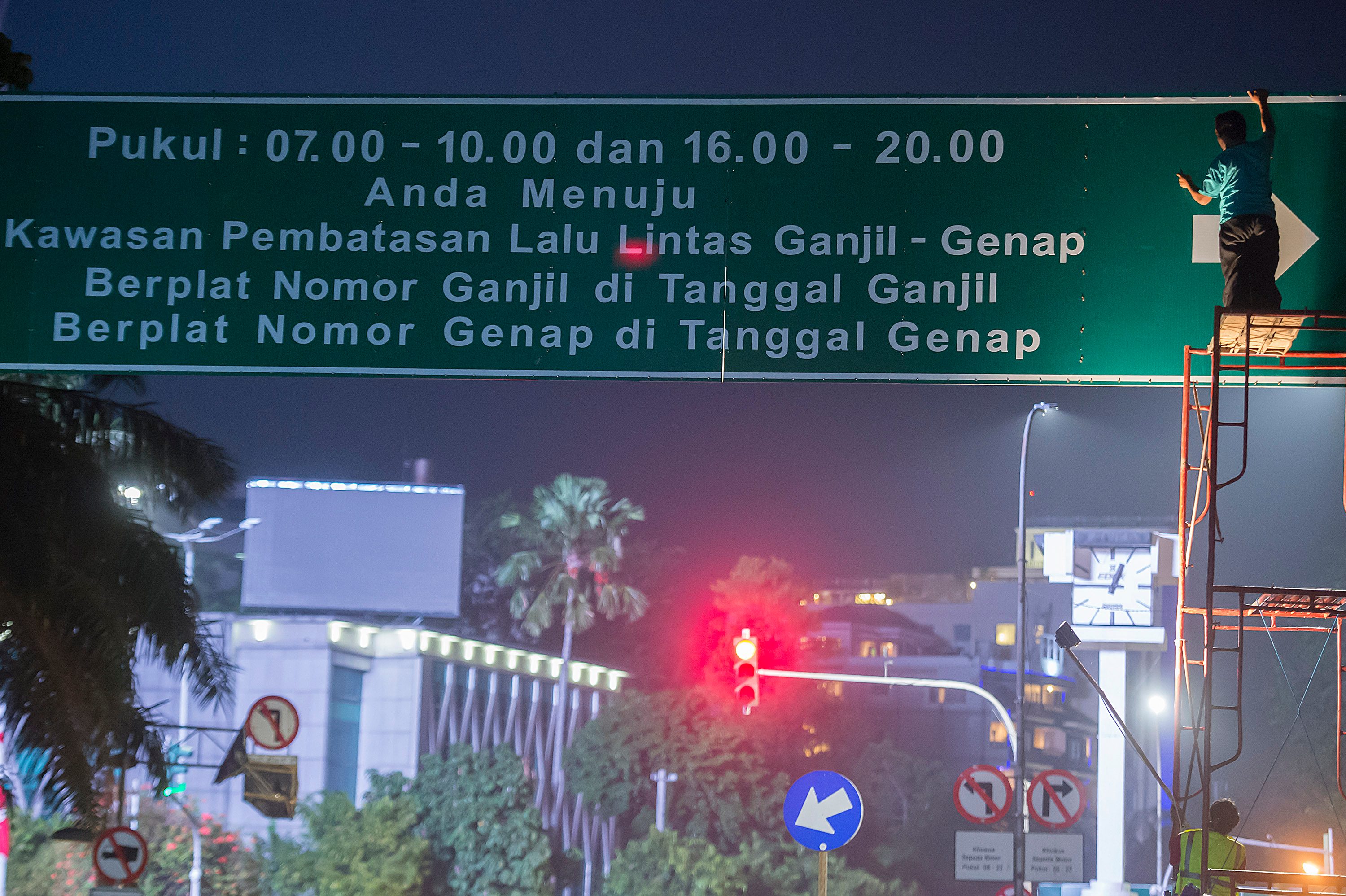 Petugas Dinas Perhubungan melakukan pekerjaan pemasangan papan informasi penerapan sistem ganjil dan genap di Jalan Kebon Sirih, Jakarta, pada 27 Agustus 2016. Foto oleh Widodo S. Jusuf/Antara 