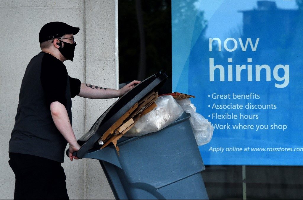 JOBS. A man wearing a face mask walks past a 'Now Hiring' sign in front of a store amid the coronavirus pandemic in Arlington, Virginia, on May 14, 2020. Photo by Olivier Douliery/AFP 