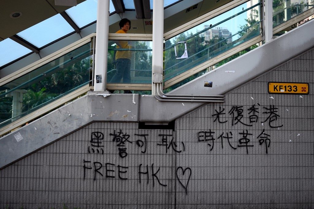 FREE HK. This picture taken on August 9, 2019 shows a woman walking on a pedestrian bridge adorned with "Free HK" graffiti in the Wong Tai Sin district of Hong Kong. Photo by Manan Vatsyayana/AFP 