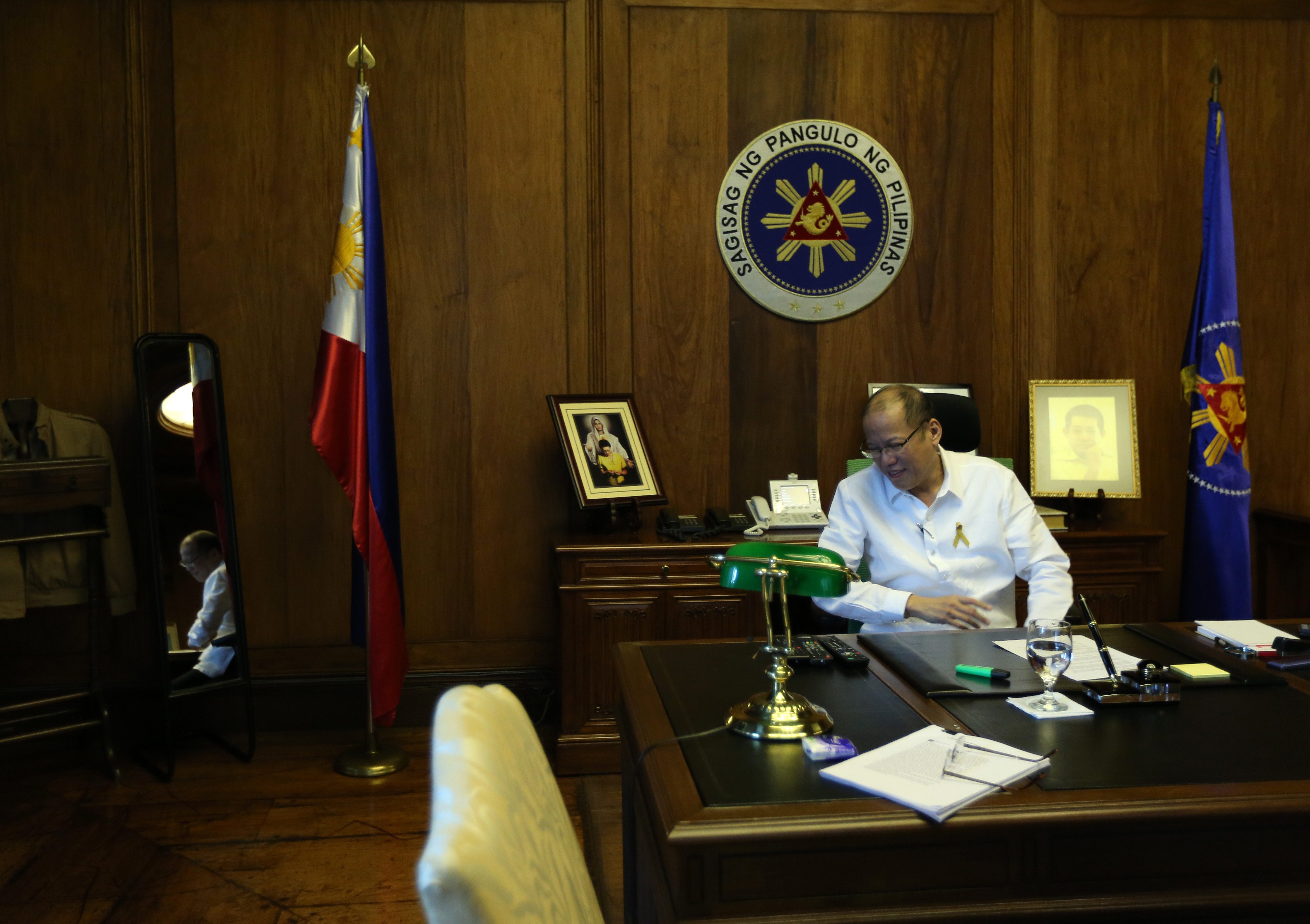 STILL WORKING. President Benigno Aquino III spends his last day in office still working. Beside him are photos of his parents. Photo by Gil Nartea/Malacañang Photo Bureau 