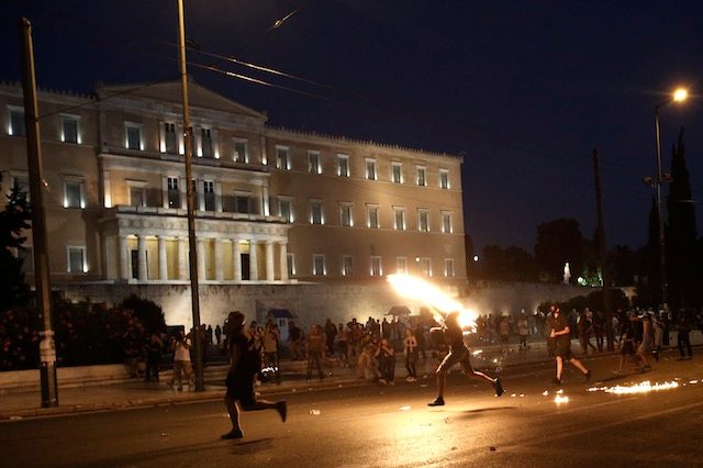 VIOLENCE OUTSIDE PARLIAMENT. Protesters throw petrol bombs to policemen in front of the parliament during a demonstration against the prior actions expected to be voted by lawmakers, in Athens, Greece, July 15, 2015. Yannis Kolesidis/EPA 