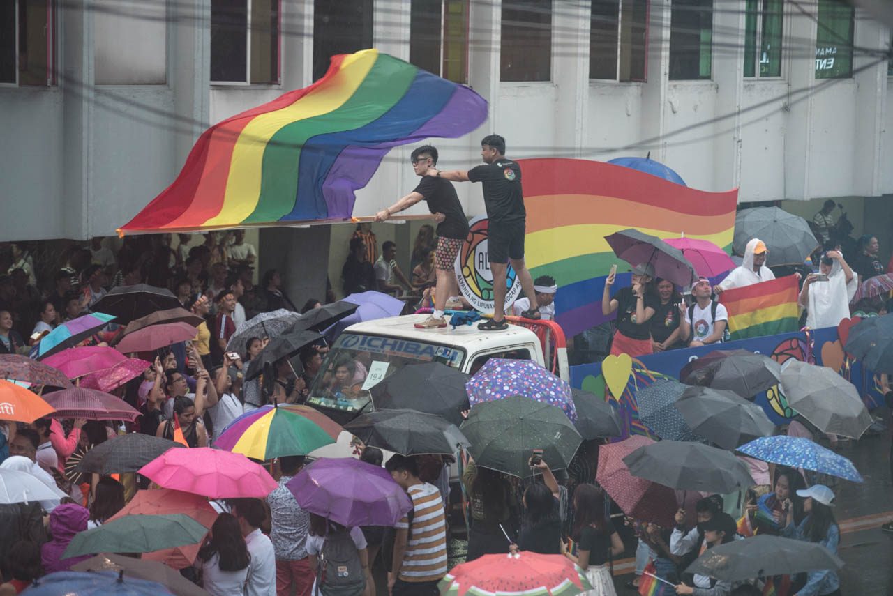 LOUD AND PROUD. A participant waves a giant Pride flag while standing at the top of one of the floats during the 2019 Metro Manila Pride March. Photo by Rob Reyes/Rappler 