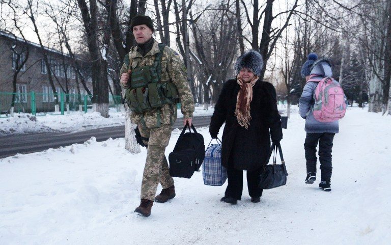 An Ukrainian serviceman help an elderly woman to carry her belongings to a tent set to warm local residents of town of Avdiivka, Donetsk region,  January 31, 2017. Aleksey Filippov/AFP 