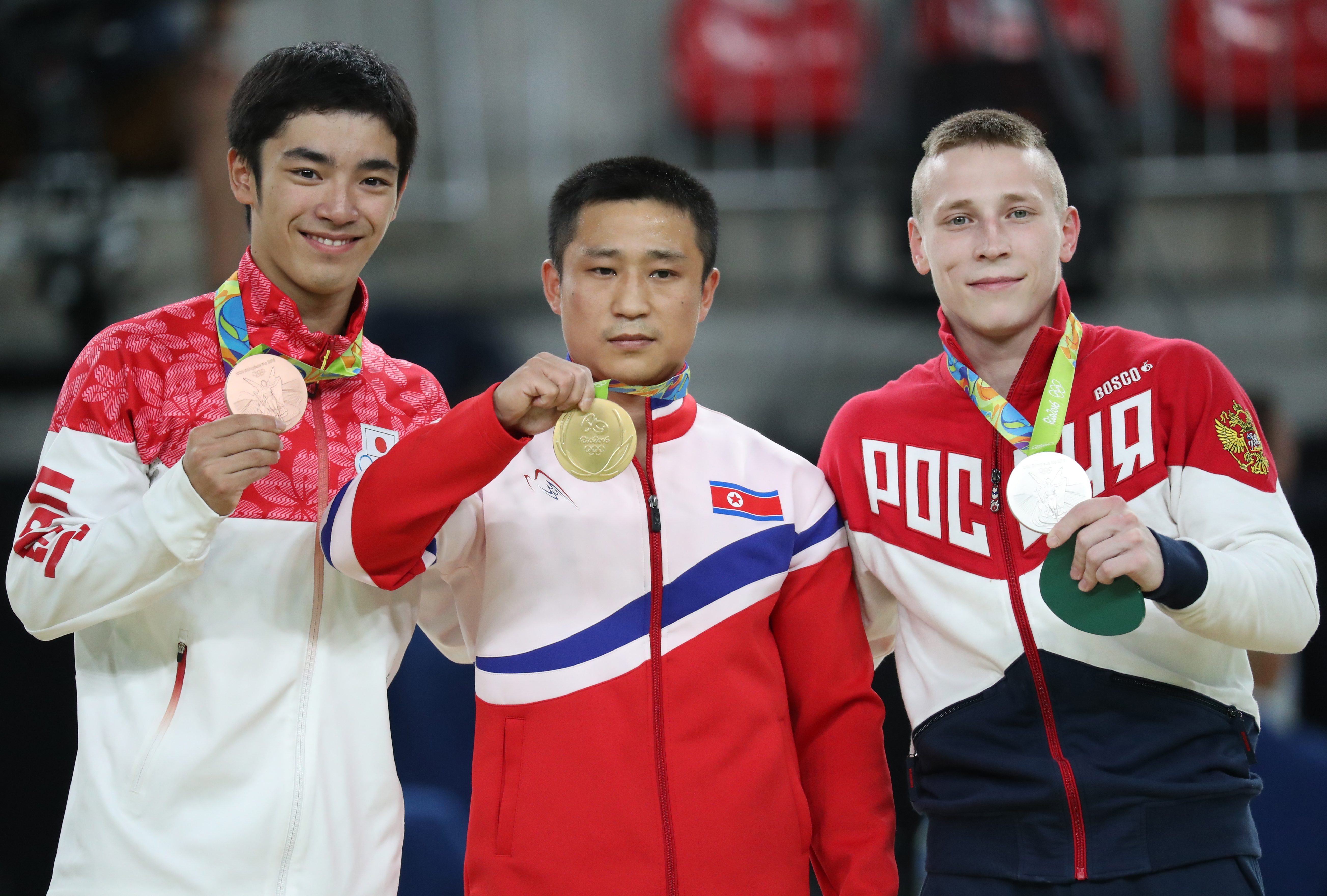 Peraih medali emas asal Korea Utara, Ri Se Gwang (tengah), tidak tersenyum saat di podium Olimpiade Rio, pada 15 Agustus 2016. Foto oleh Tatyana Zenkovich/EPA 