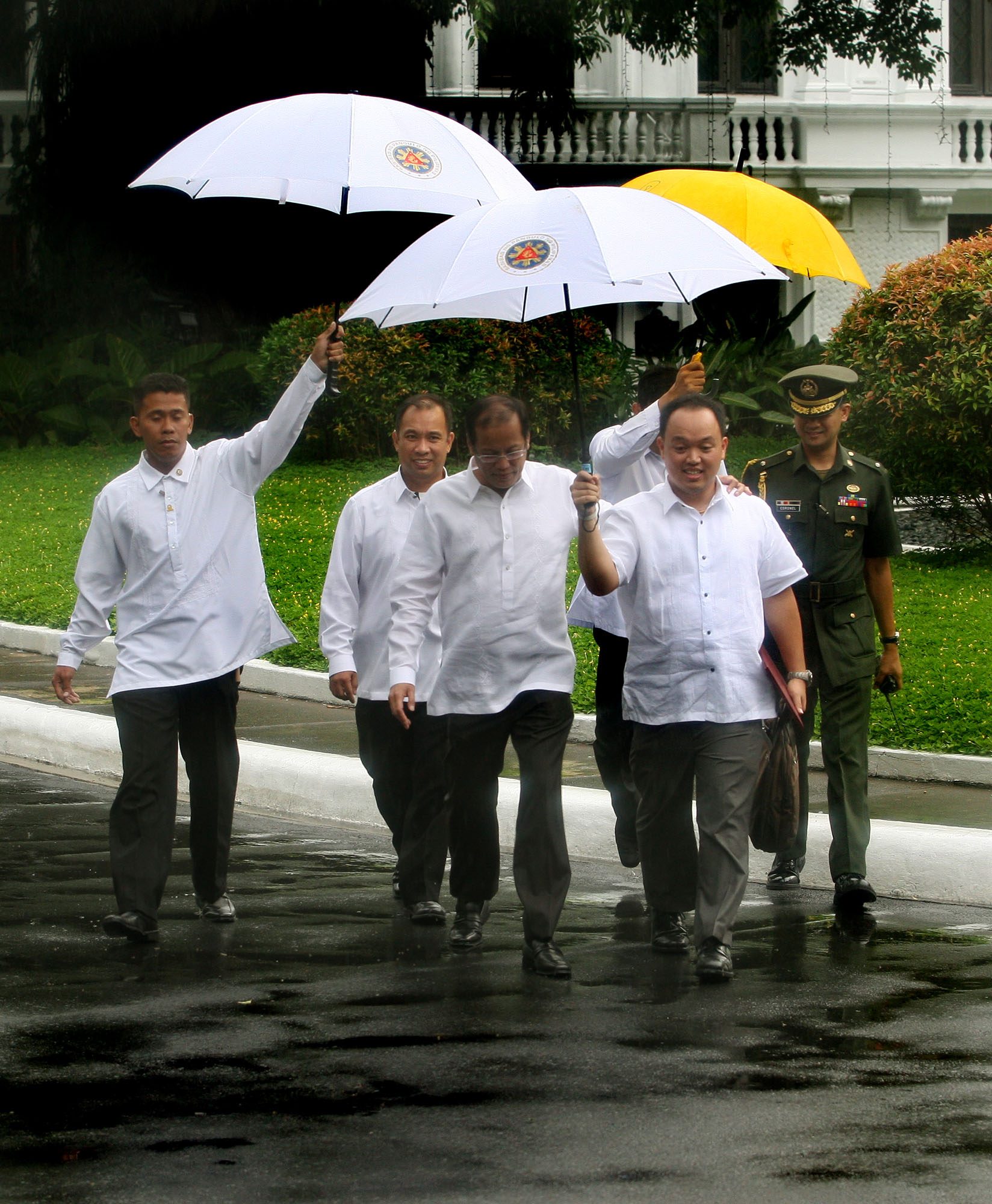 RAINY DAY. With an arm around his aide, Assistant Secretary Jun Delantar, President Aquino walks in the rain en route to the Premier Guest House in the Palace grouns on July 23, 2010      