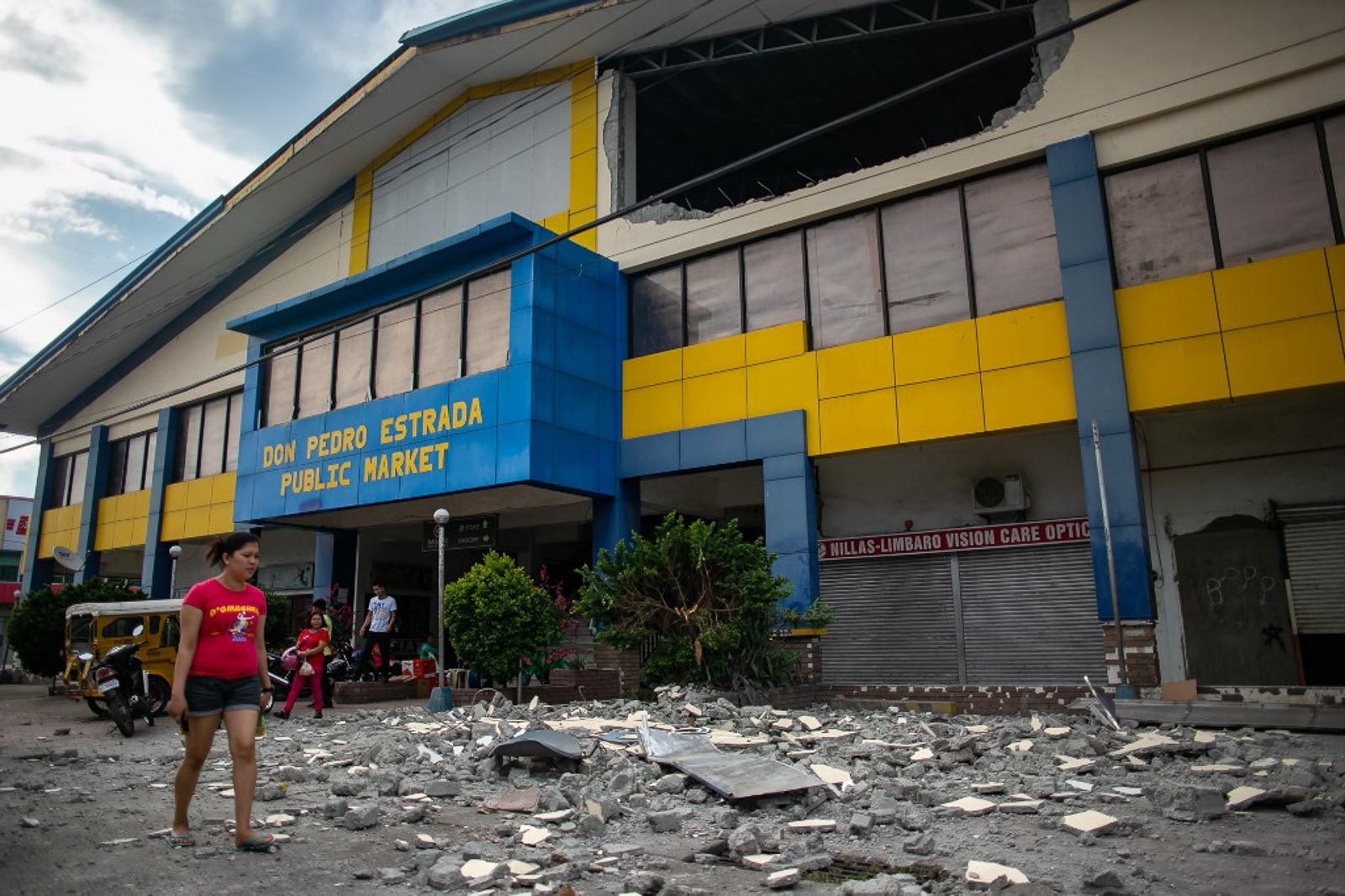 DAMAGE. A resident walks past debris from a partially damaged building in Digos, Davao del Sur, on October 17, 2019. Photo by Manman Dejeto/AFP 