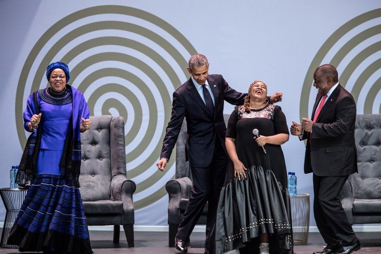 CELEBRATION. Former US President Barack Obama (2nd from left), Graca Machel (left), widow of former South African president and global icon Nelson Mandela, and South African President Cyril Ramaphosa (right) dance as South-African singer Thandiswa Mazwai performs during the 2018 Nelson Mandela Annual Lecture at the Wanderers cricket stadium in Johannesburg on July 17, 2018. Photo by Marco Longari/AFP   