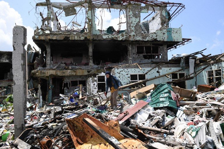 MARAWI SCENE. A resident stands among the rubbles of her destroyed house, as she tries to salvage belongings during a visit to the main battle area in Marawi City. File photo by Ted Aljibe/AFP    