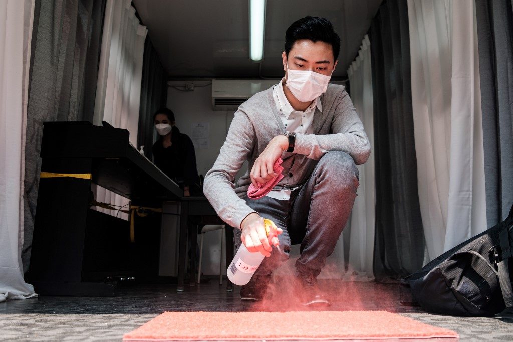 CLEANING. In this photo taken on April 10, 2020, piano teacher Evan Kam, 28, wears a face mask, as a precautionary measure against the COVID-19 coronavirus, as he sanitises a shoe mat at the entrance of his 
 piano truck. Photo by Anthony Wallace/AFP 