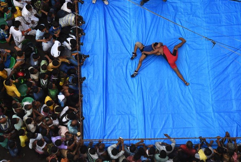 DIWALI FESTIVAL. Indian amateur wrestlers participate in a friendly wrestling competition on a make-shift ring at the junction of a busy road organised as part of Diwali festivities in Kolkata on October 18, 2017. Photo by Dibyangshu Sarkar/AFP  